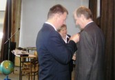 Burmistrz Janusz Dąbrowski przypina tarczę szkoły nauczycielowi Andrzejowi Zadorożnemu.