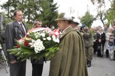 Kwiaty pod tablicą składa zastępca burmistrza Bogdan Wołoszyn.